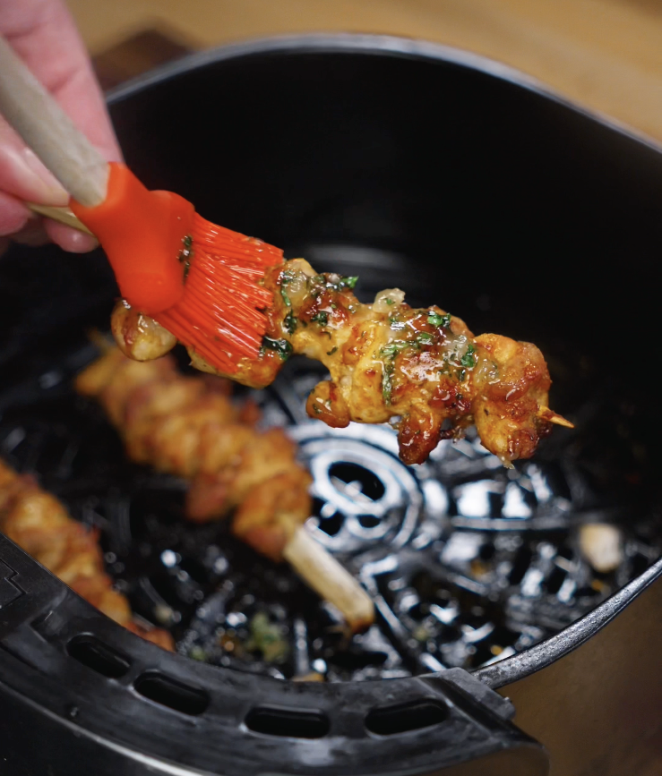 Cooked chicken skewers are brushed with glossy garlic honey butter glaze for extra flavor.