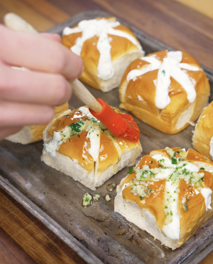 Garlic butter mixture is brushed onto the filled bread rolls before baking to create a golden, flavorful crust.