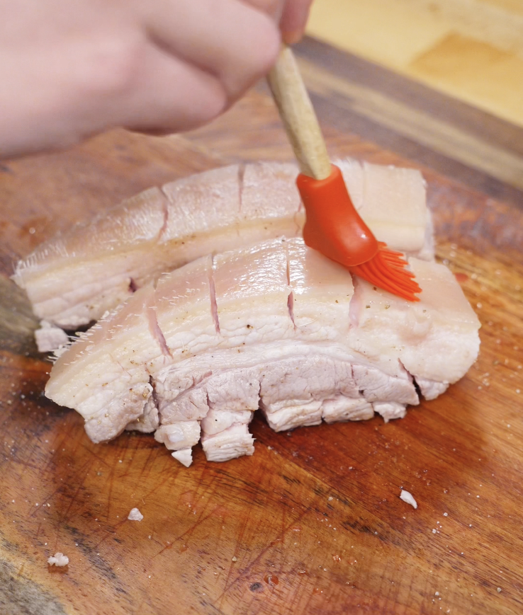 Pork belly skin is brushed with vinegar using a silicone brush to help it crisp up in the air fryer.
