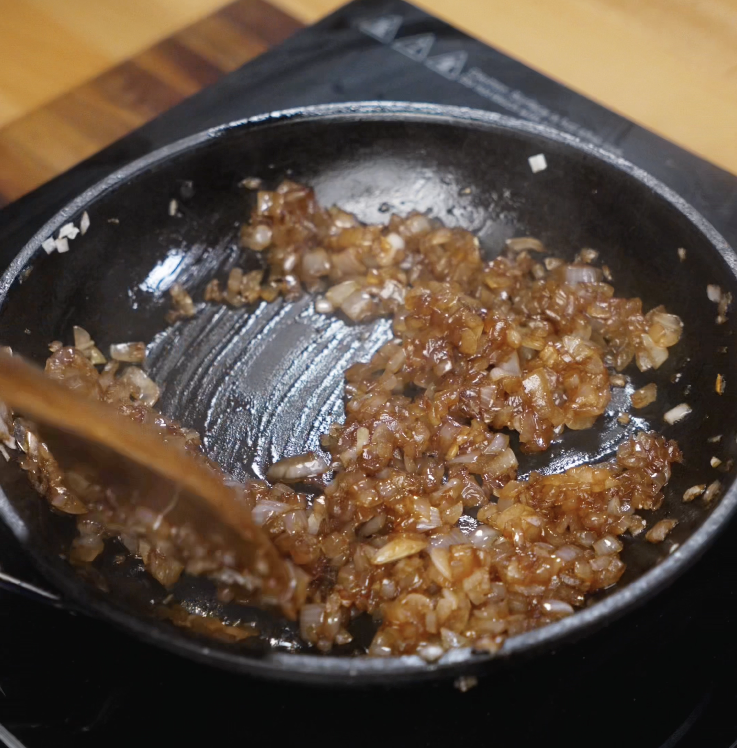 Finely diced onions are being slowly caramelized in a pan until golden brown and jammy.