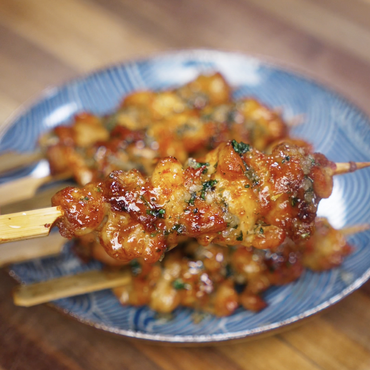 A close-up shot shows the sticky, caramelized garlic honey butter coating on each chicken skewer.