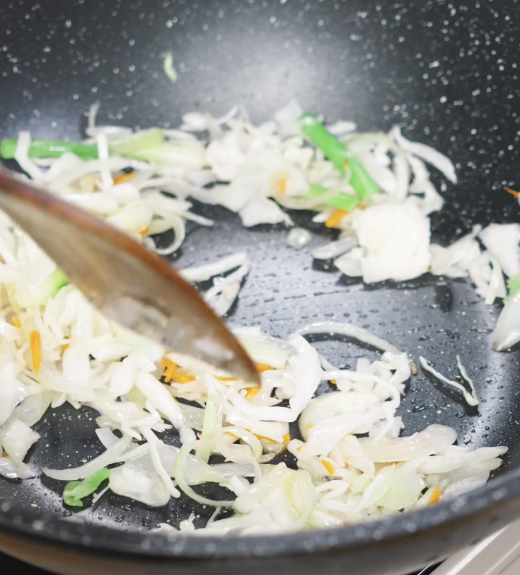 Shredded cabbage and carrots are stir-fried in the wok until wilted, adding color and texture to the chow mein.