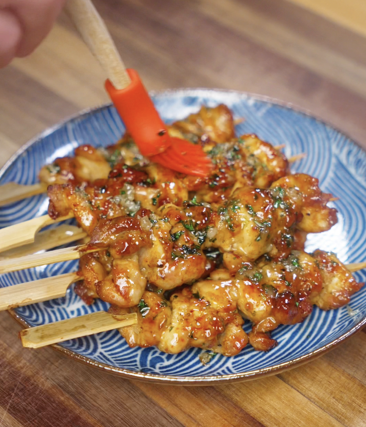The finished chicken skewers get one last brush of garlic honey butter sauce before serving.
