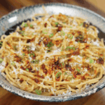 A finished bowl of miso butter pasta garnished with scallions, chili crunch, and parmesan, highlighting its rich umami flavor and glossy texture.