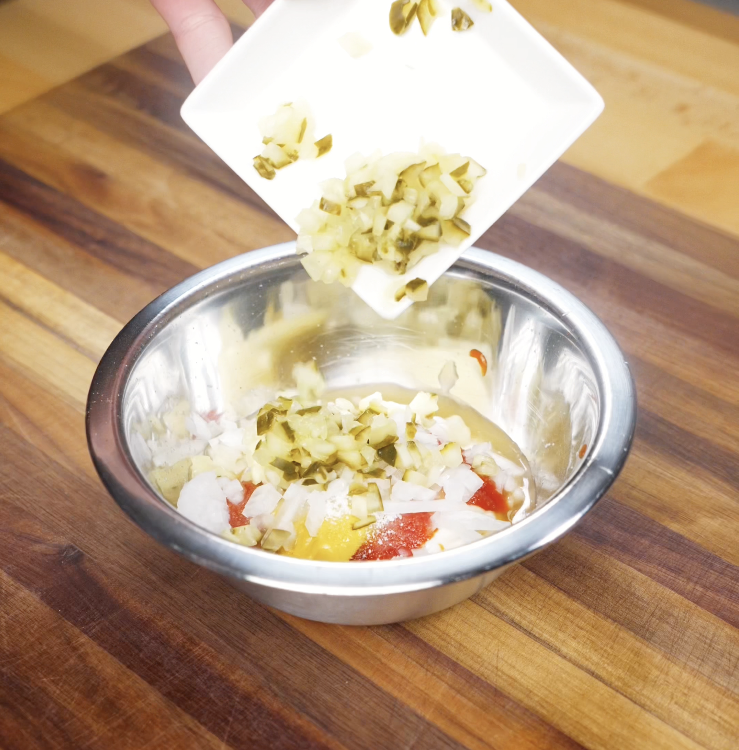 Chopped pickles are added to a bowl of mayo, ketchup, gochujang, and onions to make the tangy animal-style sauce.