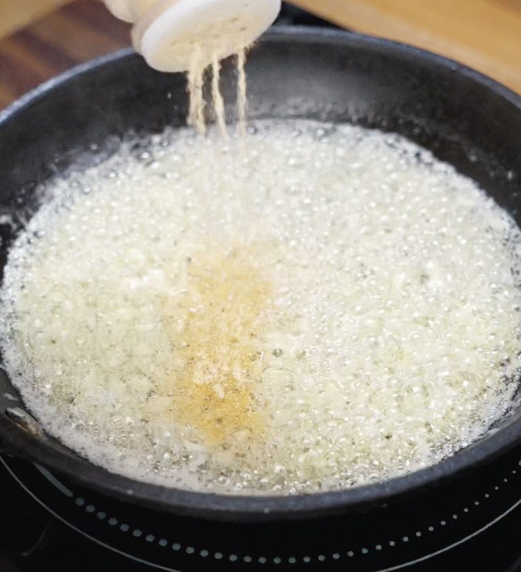 Garlic powder is added to bubbling melted butter in a skillet to build the rich and aromatic garlic butter sauce.