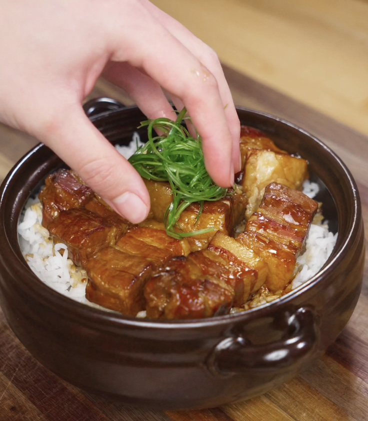 Thinly sliced scallions are arranged on top of the finished braised pork belly for a fresh, aromatic garnish.