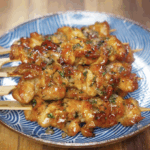 Glazed garlic honey butter chicken skewers are plated on a blue patterned dish for serving.