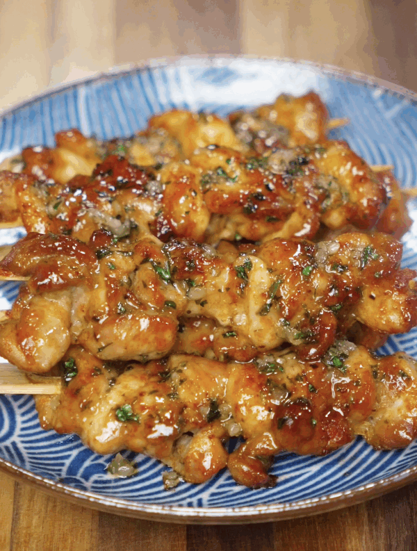 Glazed garlic honey butter chicken skewers are plated on a blue patterned dish for serving.