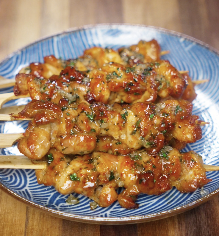 Glazed garlic honey butter chicken skewers are plated on a blue patterned dish for serving.