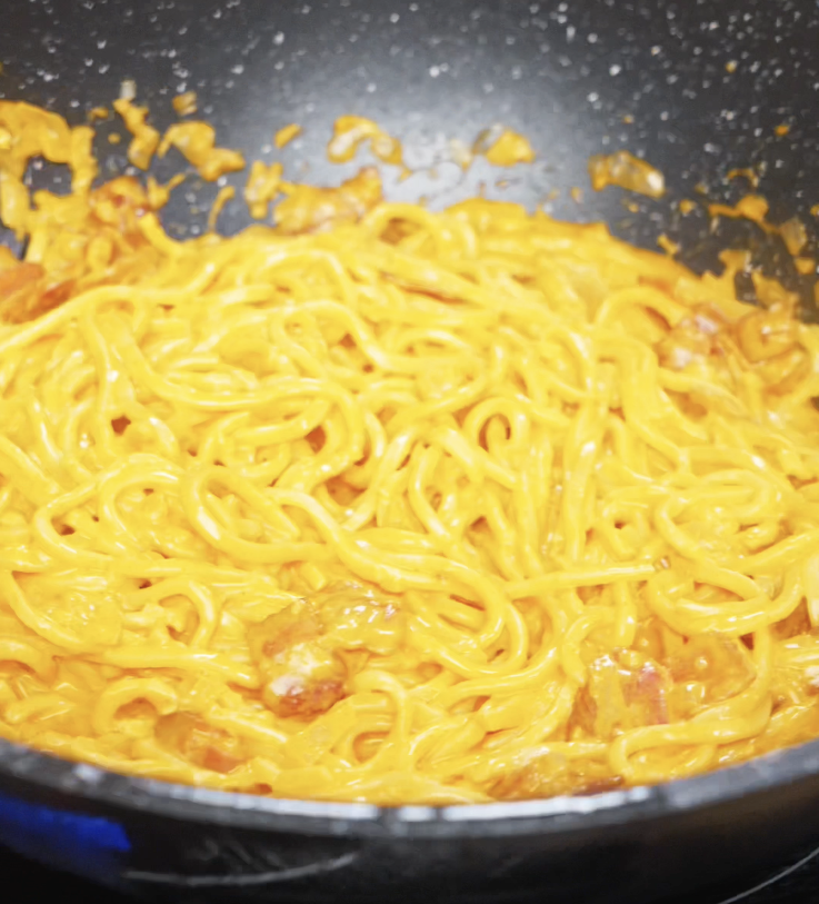 Freshly cooked noodles are tossed in a thick, creamy gochujang sauce until evenly coated and glossy.