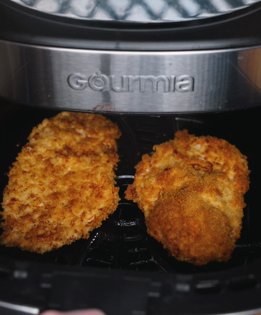 Chicken katsu cooking inside the air fryer, turning golden brown and crisp as hot air circulates for an evenly cooked crust.