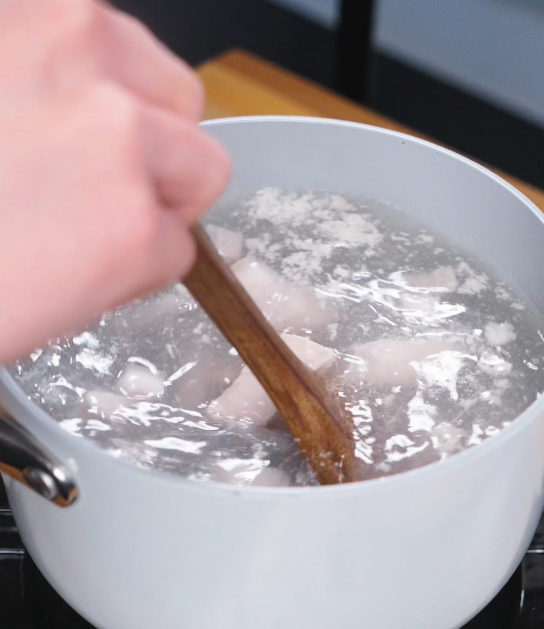 Cubed pork belly being blanched in boiling water to remove impurities, an essential first step for clean flavor and tender red braised pork.