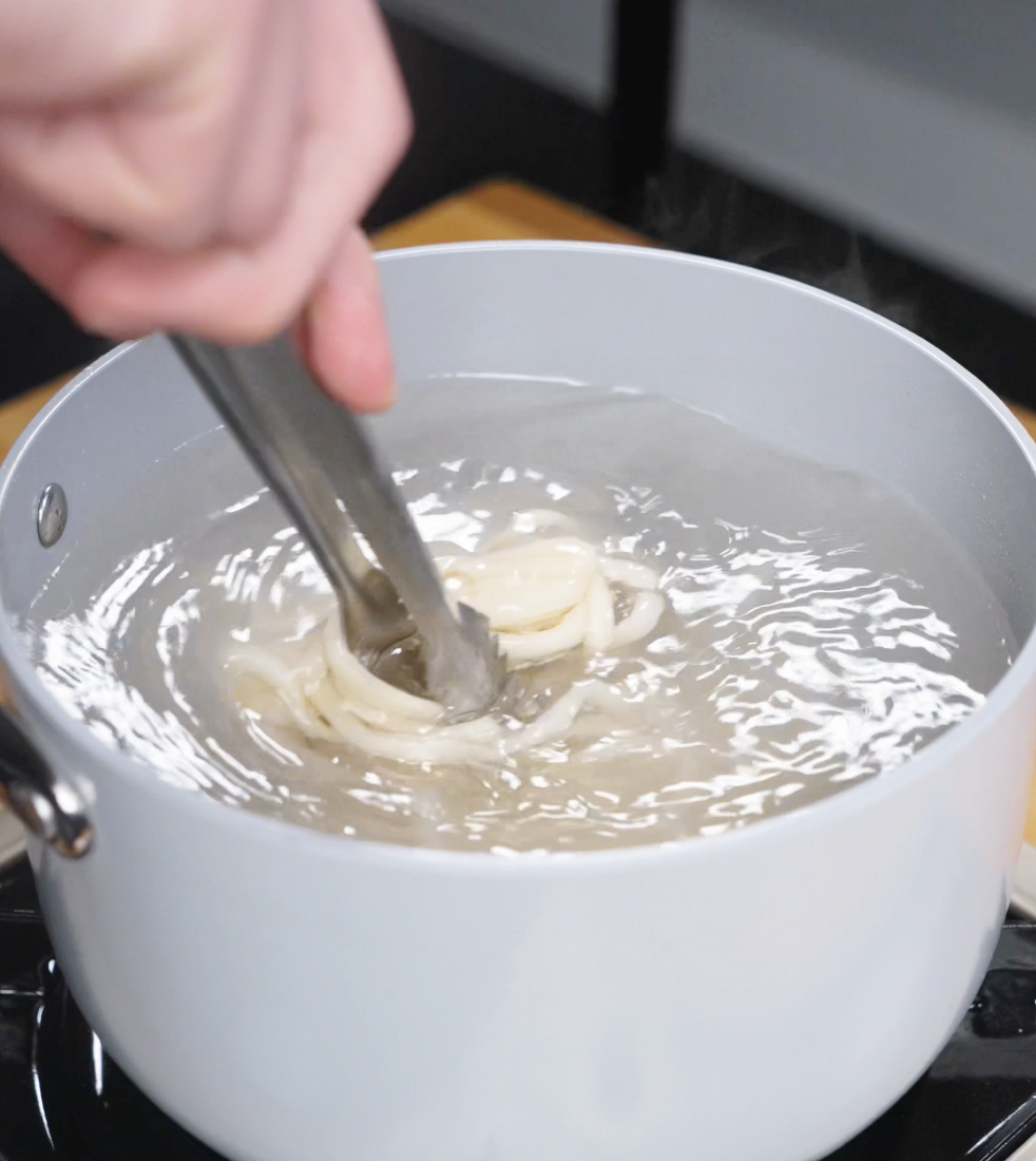 A pot of bubbling water with noodles cooking until al dente, ready to soak up the rich brown butter miso sauce.