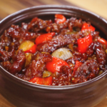 A hearty bowl of glossy Beijing Beef with bell peppers and onions, coated in sweet-savory sauce, ready to be served.