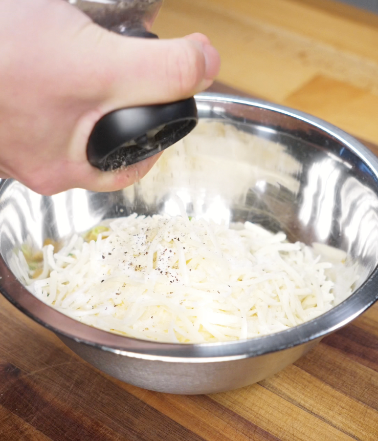 A creamy mixture of corn, mayo, cheese, and scallions being stirred together before baking Korean corn cheese.