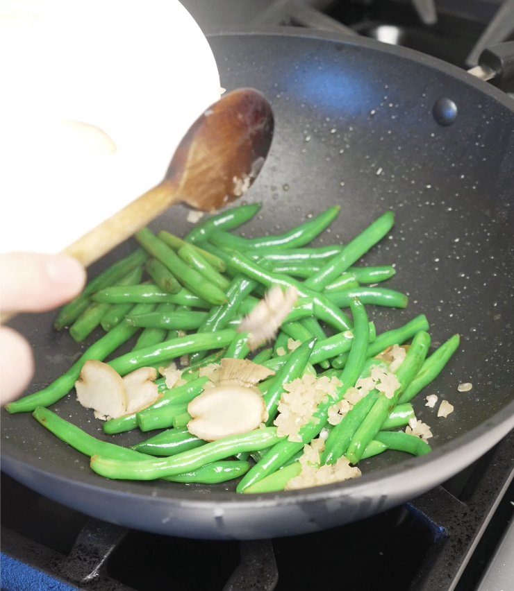Minced garlic and sliced ginger added to stir fried string beans to build aroma and depth in a classic Chinese-style chicken stir fry.