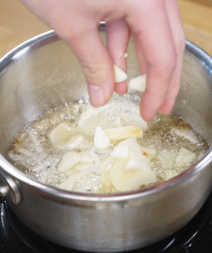 Onion, ginger, and sliced garlic sizzling in neutral oil as they turn deeply golden and fragrant to make the signature golden oil for this soy-forward chicken dish.