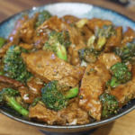 Finished beef and broccoli coated in a glossy brown sauce, with tender beef slices and crisp broccoli florets.