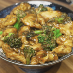Chicken and broccoli coated in a glossy brown sauce served over rice in a ceramic bowl for a healthy high-protein Asian dinner.