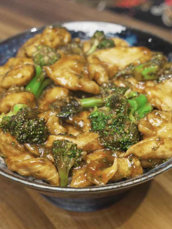 Chicken and broccoli coated in a glossy brown sauce served over rice in a ceramic bowl for a healthy high-protein Asian dinner.