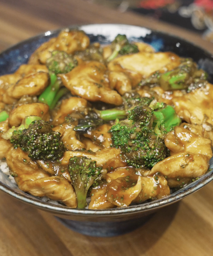 Chicken and broccoli coated in a glossy brown sauce served over rice in a ceramic bowl for a healthy high-protein Asian dinner.