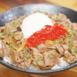 Finished gyudon bowl with thinly sliced beef and onions simmered in a sweet soy broth, topped with pickled ginger, scallions, and an onsen egg over rice.