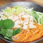 Finished Vietnamese chicken salad made with tender shredded chicken, crisp vegetables, rice noodles, fresh mint, and a tangy fish sauce dressing as a healthy Asian dinner.