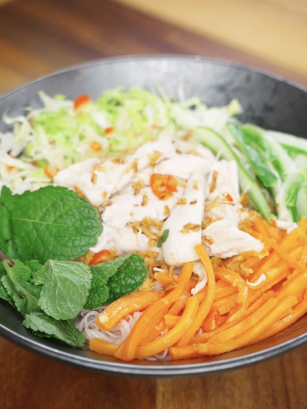 Finished Vietnamese chicken salad made with tender shredded chicken, crisp vegetables, rice noodles, fresh mint, and a tangy fish sauce dressing as a healthy Asian dinner.