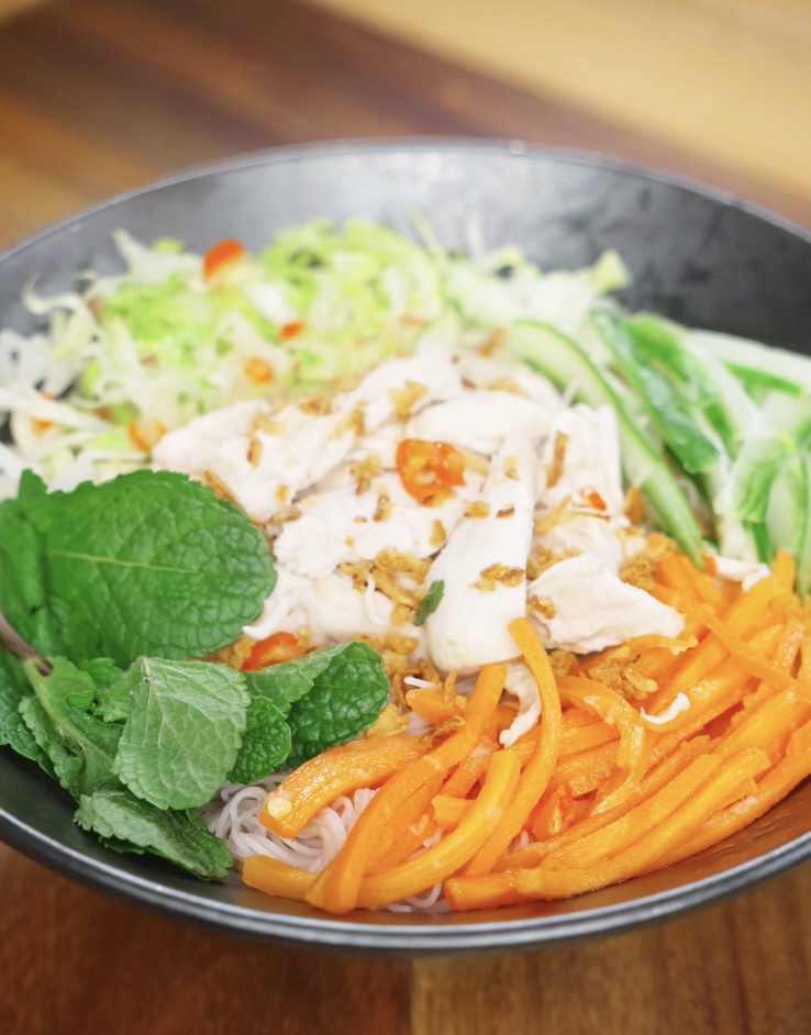 Finished Vietnamese chicken salad made with tender shredded chicken, crisp vegetables, rice noodles, fresh mint, and a tangy fish sauce dressing as a healthy Asian dinner.