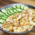 Finished golden oil poached chicken served over steamed rice, topped with tender juicy chicken thighs and a glossy soy-forward golden oil sauce with caramelized onion and garlic for a comforting high-protein Asian dinner.