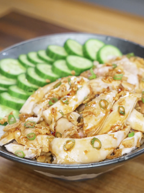 Finished golden oil poached chicken served over steamed rice, topped with tender juicy chicken thighs and a glossy soy-forward golden oil sauce with caramelized onion and garlic for a comforting high-protein Asian dinner.