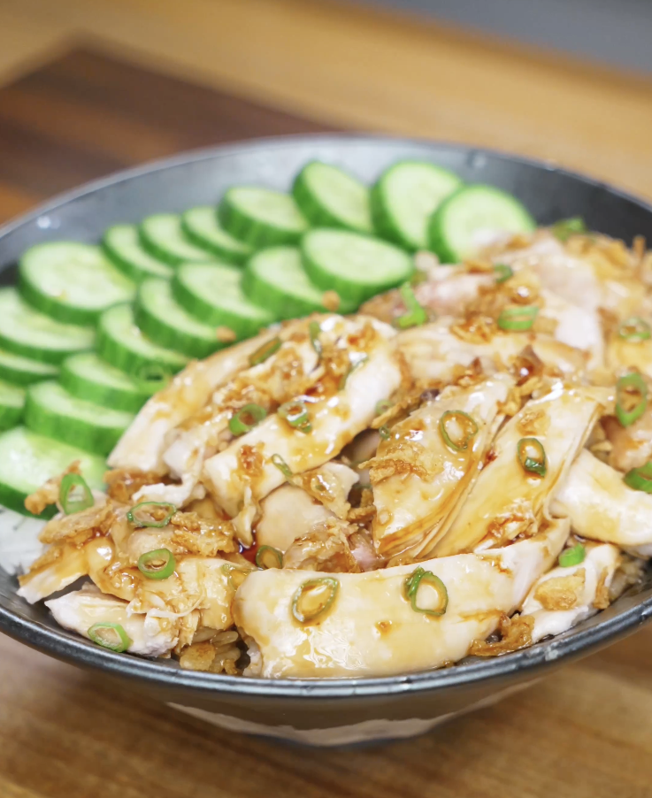 Finished golden oil poached chicken served over steamed rice, topped with tender juicy chicken thighs and a glossy soy-forward golden oil sauce with caramelized onion and garlic for a comforting high-protein Asian dinner.