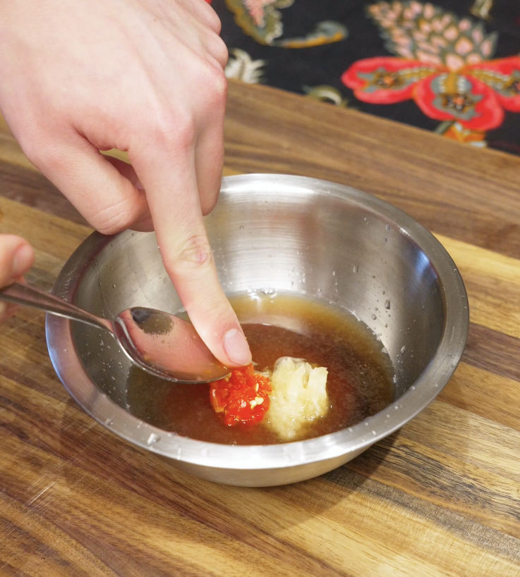 Fish sauce, water, sugar, lime juice, garlic, and chopped Thai chilies combined in a bowl to make Vietnamese nuoc cham sauce.