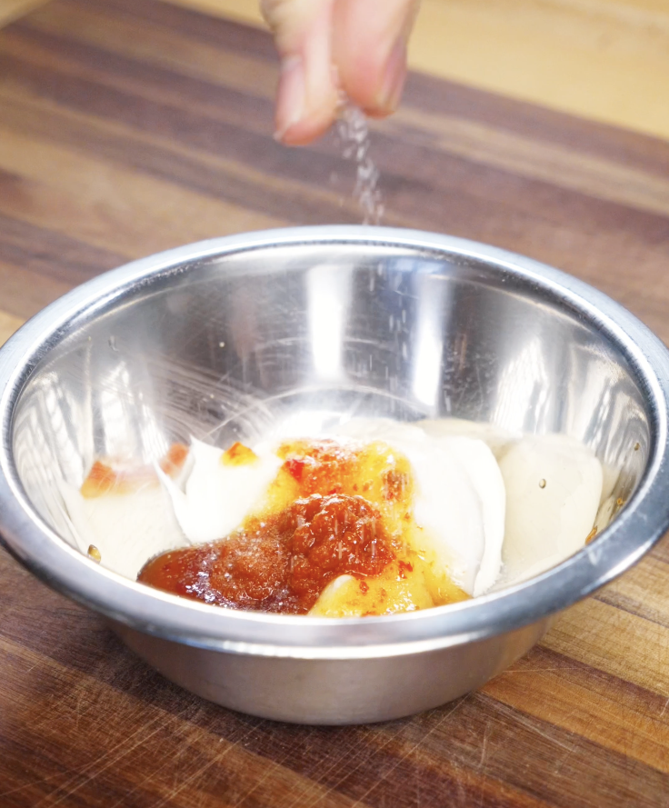 Bang bang sauce being mixed in a bowl with mayo, Thai chili sauce, sriracha, and salt, creating a creamy and spicy sauce for Bang Bang Shrimp.