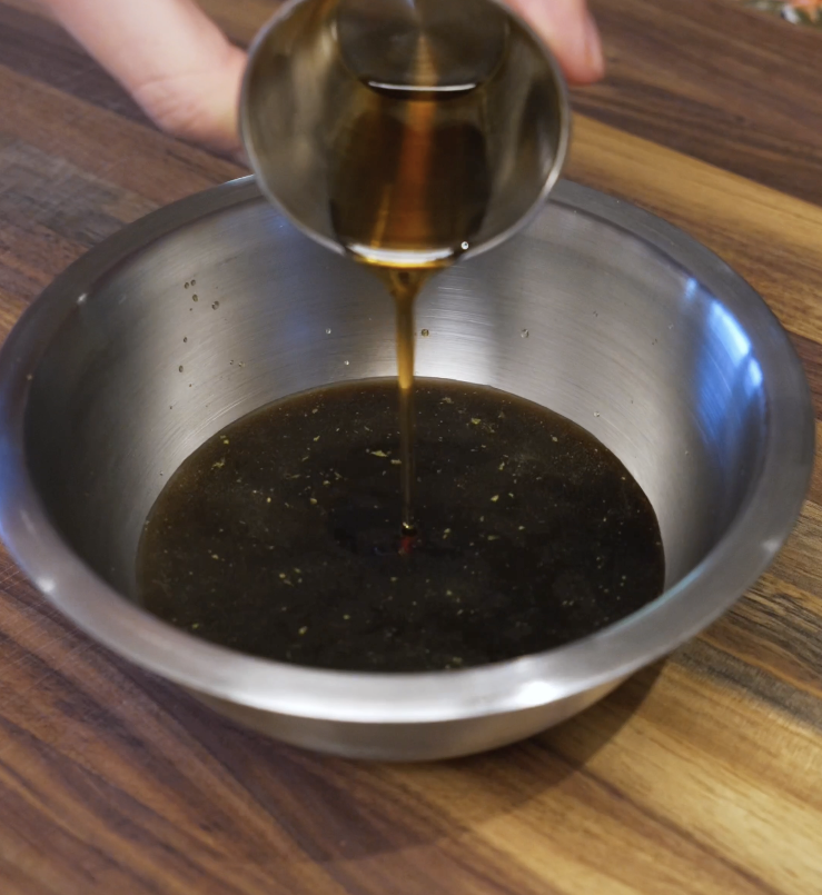 Soy-based beef and broccoli sauce being poured into a bowl, combining chicken broth, soy sauce, sesame oil, garlic, ginger, and sugar.