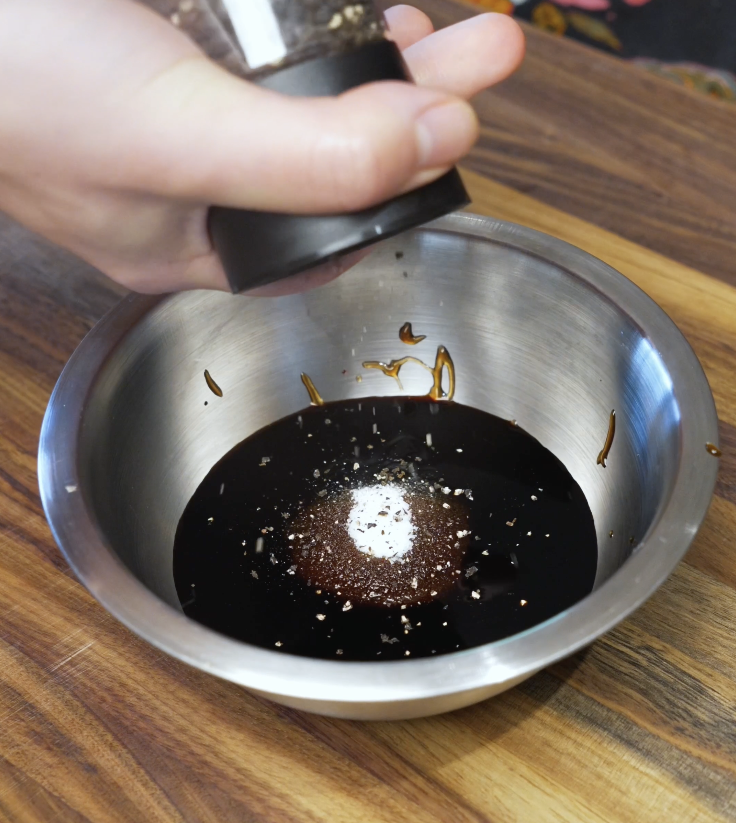 Bowl of stir fry sauce made with soy sauce, oyster sauce, sugar, and black pepper being seasoned and mixed.