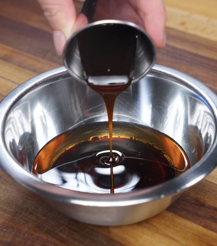 Hot infused golden oil being mixed with soy sauce, sesame oil, oyster sauce, and sugar to create a glossy savory sauce for golden oil poached chicken.