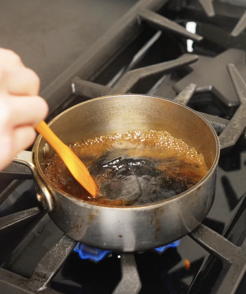 Soy sauce, mirin, sake, and sugar simmering in a small saucepan as bubbles form, reducing into a glossy Japanese-style steak sauce.