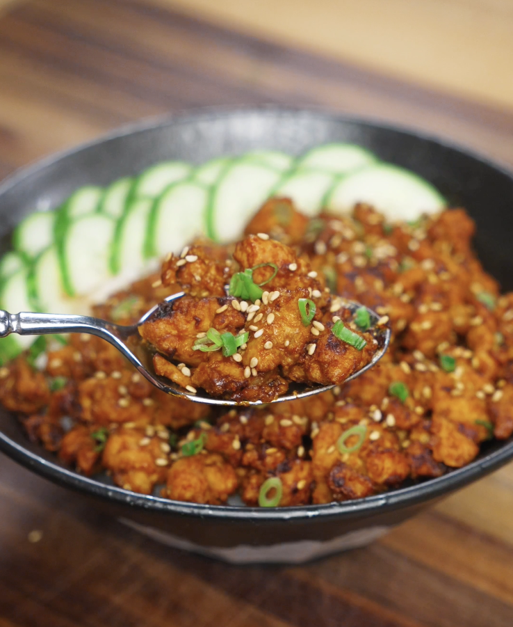Spoonful of Spicy Peanut Chicken showing creamy peanut sauce-coated ground chicken over rice, highlighting texture and richness.