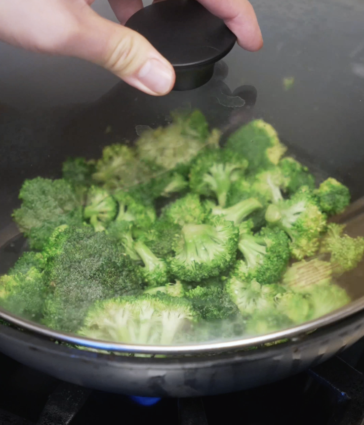 Broccoli florets steaming in a covered pan until vibrant green and just tender for classic beef and broccoli.