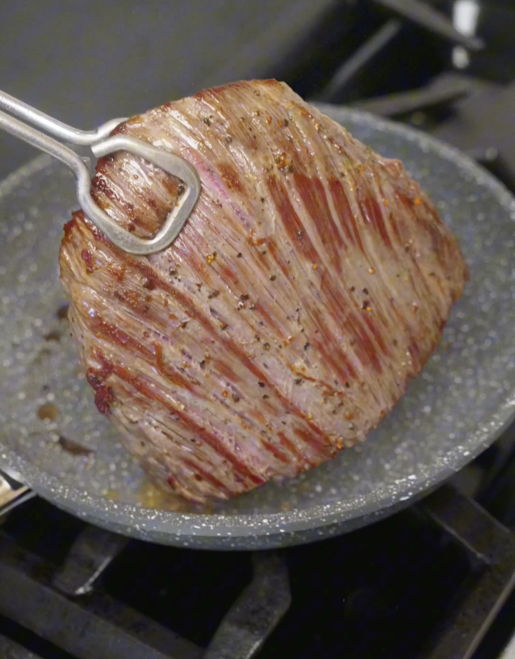 Searing flank steak in a hot pan, developing a caramelized crust while keeping the inside juicy for Thai beef salad.