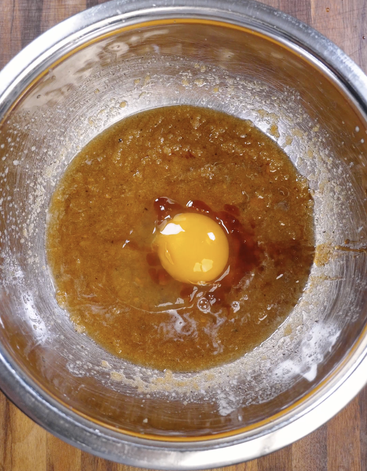 Egg and vanilla extract added to the brown butter sugar mixture, ready to be whisked into a thick and emulsified cookie dough.