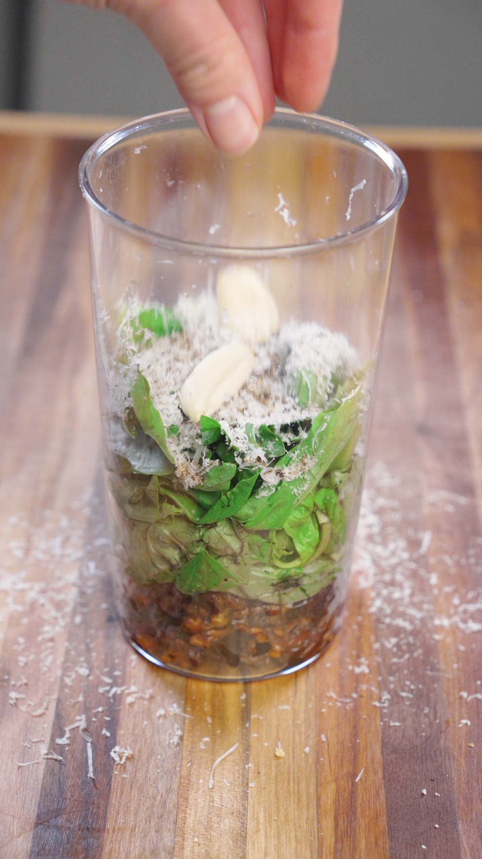 Fresh basil, grated Parmesan cheese, garlic cloves, and toasted walnuts layered in a blending cup to make homemade walnut basil pesto.