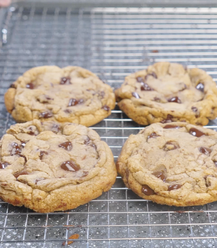 Freshly baked brown butter chocolate chip cookies cooling on a wire rack with golden edges and melted chocolate chunks.