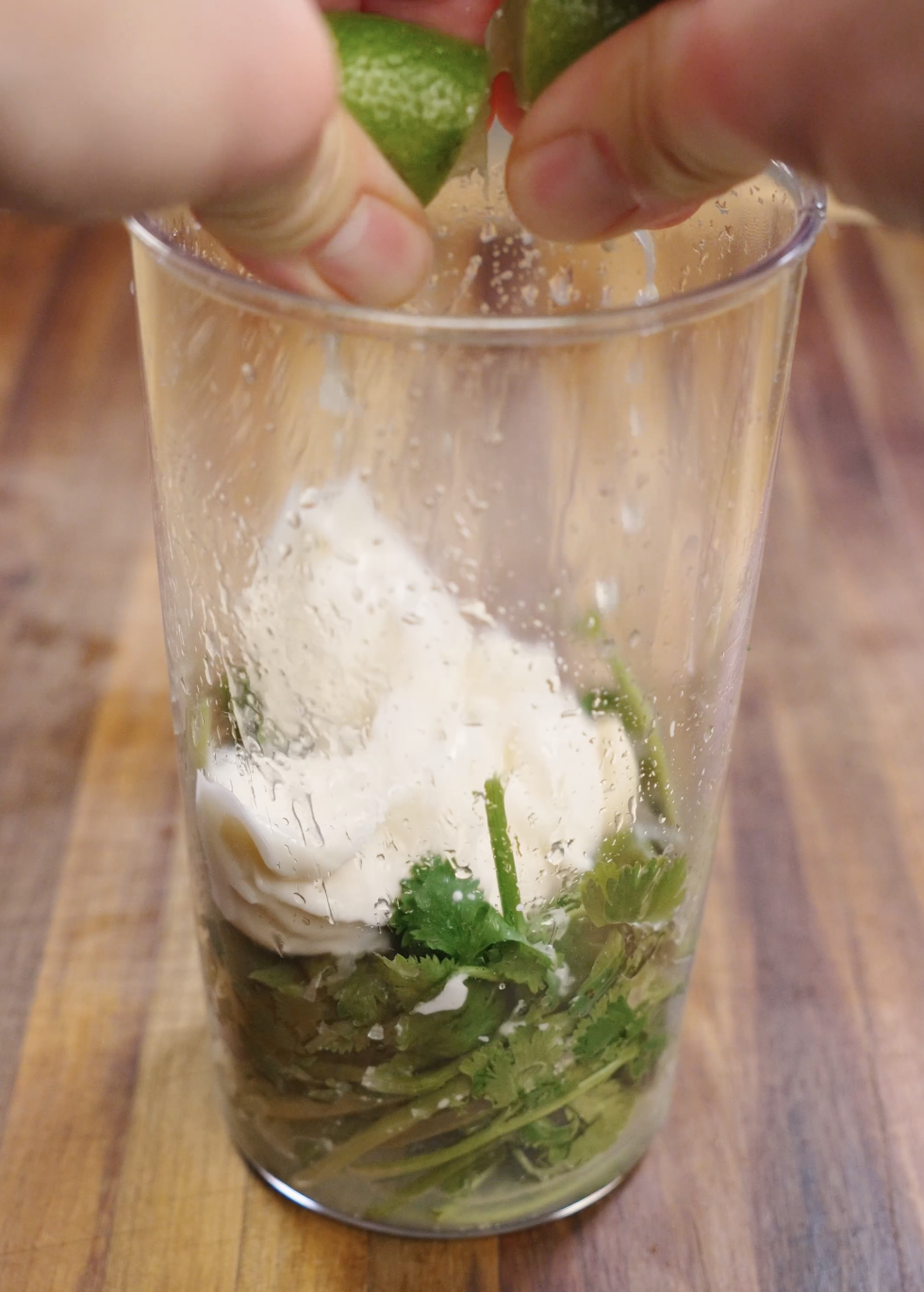 Fresh cilantro, mayonnaise, lime juice, salt, and water blended together in a tall container to create a smooth and creamy cilantro mayo sauce for crispy chicken tacos.