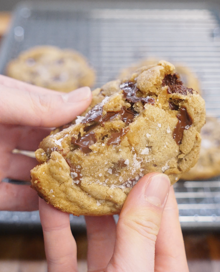Brown butter chocolate chip cookie broken open to reveal a soft, chewy center with melted chocolate and a tender crumb.