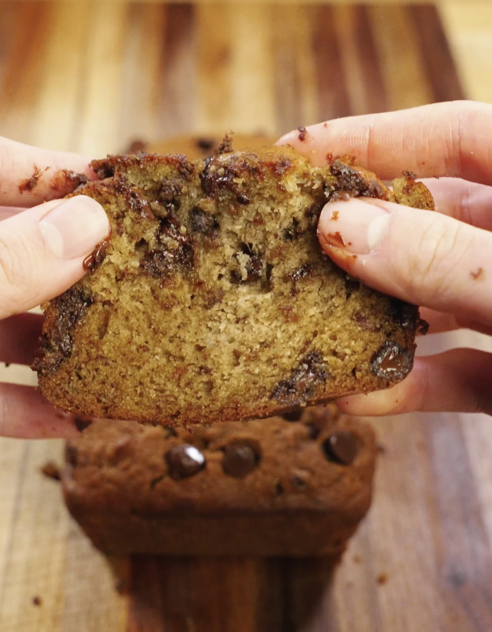 Chocolate chip banana bread slice pulled apart to show a soft, moist crumb filled with melted chocolate chips and rich banana flavor.