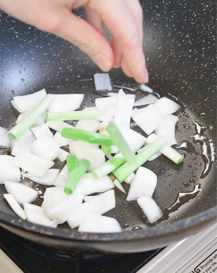 Thick onion wedges and scallion whites saut&eacute;ing in the same pan used for the chicken to build flavor for Chicken Onion Stir Fry.