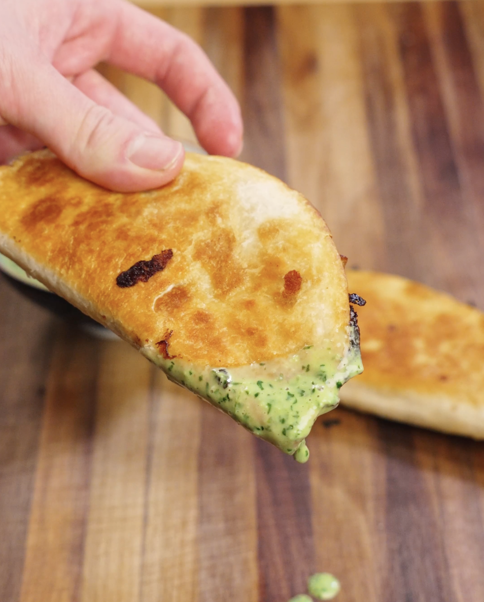 Golden crispy chicken taco folded in a flour tortilla and filled with juicy seasoned chicken, melted cheese, and a generous drizzle of creamy cilantro mayo sauce, ready to serve.